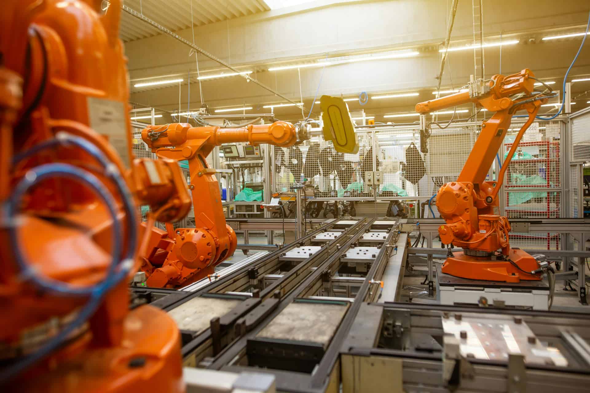 Orange industrial robot arms on an automated production line